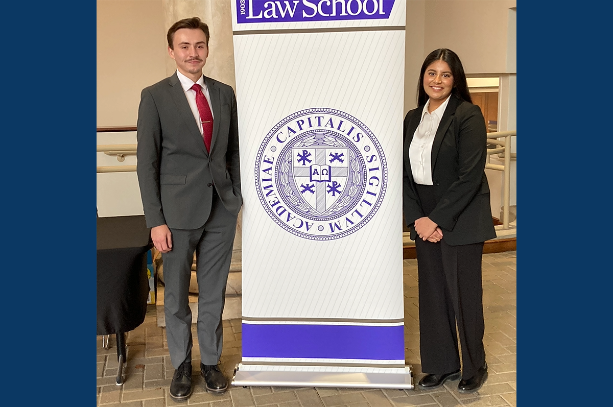 male and female young adults in business attire flanking stand-up banner